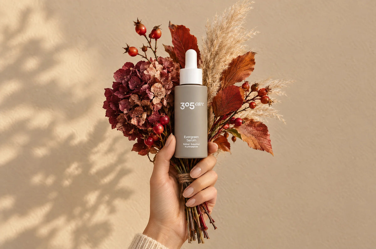 Hand hält das Evergreen Serum von 305 Care mit einem Strauß aus Herbstblättern, Hortensie und Hagebutten